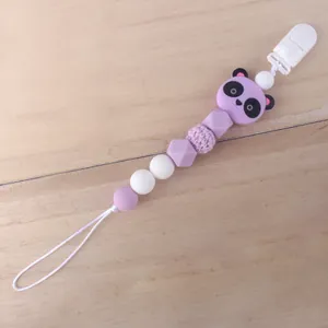 Detalle de sujetachupetes de silicona violeta con cuenta de panda sobre fondo de madera