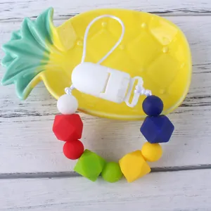 Colorful silicone teething pacifier clip with diverse beads on a wooden background