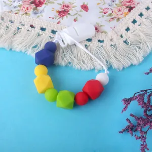 Close-up of colorful silicone pacifier clip with diverse beads on a soft blue background