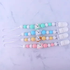 Flat lay of four silicone pacifier clips with unicorn motifs in pastel colors