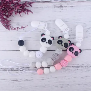 Sujeta chupetes de silicona con diseño de panda y cuentas de colores sobre madera blanca