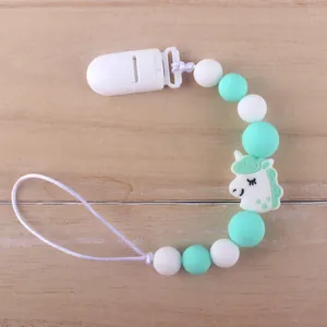 Detail of silicone pacifier clip with mint green beads and a cartoon unicorn charm