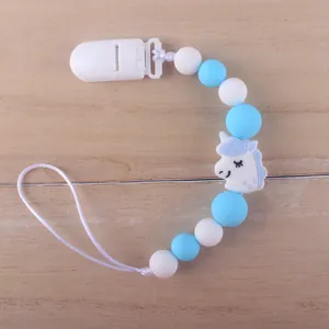 Detail of baby silicone pacifier clip with blue beads and white unicorn pendant