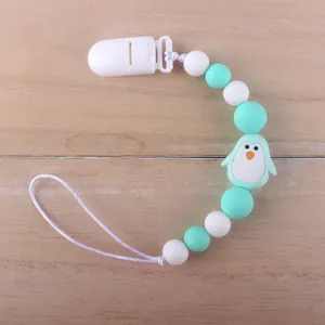 Detail of silicone baby pacifier clip with mint green beads and cute penguin pendant