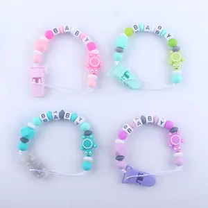 Detalle de sujetachupetes de silicona con cuentas de letras BABY en cuatro colores