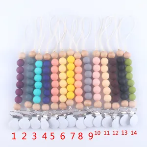 Flat lay of 14 colorful silicone and wooden baby pacifier clips with secure clips