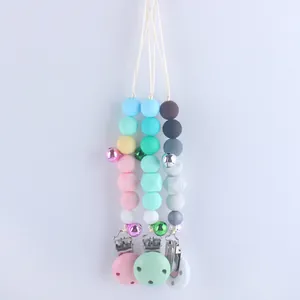 Three colorful silicone pacifier clips with geometric beads and small metal bells