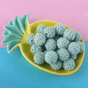 Macro detail of 16mm mint green hand-crocheted wooden beads for DIY jewelry making