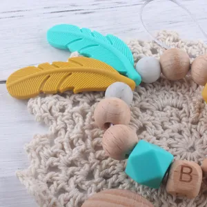 Détail des perles en silicone et bois de hêtre avec pendentif plume pour bébé