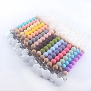 Silicone and wooden baby pacifier clips in various colors arranged on white background