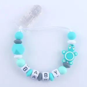 Detalle del sujetachupete de silicona con cuentas de letras BABY y tortuga