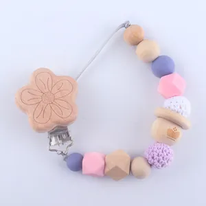 Detailed close-up of a silicone pacifier clip with natural wooden beads and knitted balls