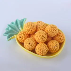 Close-up of orange crochet beads on a pineapple dish for DIY jewelry making crafts