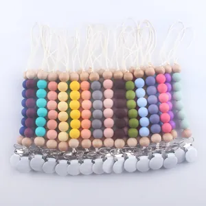 Flat lay showing various colorful silicone and wood baby pacifier clips in 15+ shades