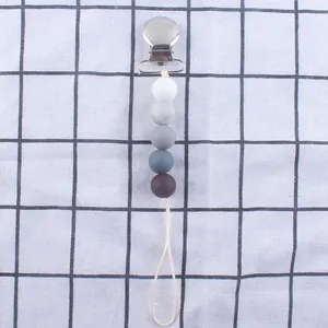 Nahaufnahme von Schnullerkette mit Metallclip und Silikonperlen in Grauverlauf-Optik