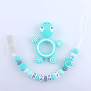 Detail of turquoise silicone turtle teether with a pacifier clip featuring baby letter beads