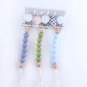 Silicone baby pacifier clips in purple, olive green, and blue with natural wood beads