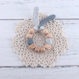 Détail d'une attache-tétine pour bébé avec perles en hêtre et plumes en silicone
