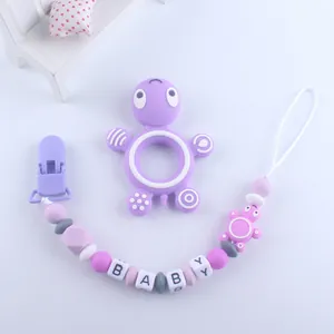 Close-up of a purple silicone turtle teether and baby letter bead pacifier clip set