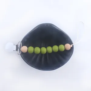 Detail of silicone and wood beads pacifier clip inside a black decorative shell tray