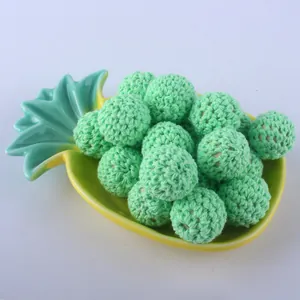 Detail of 20mm mint green crochet covered beads arranged in a yellow pineapple tray