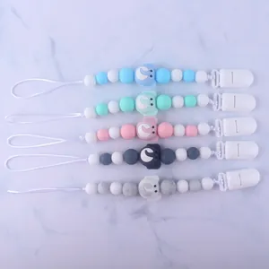 Silicone baby pacifier clips with elephant beads in five colors on marble background