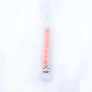 Detail of peach silicone and wooden beads baby pacifier clip with secure metal fastener