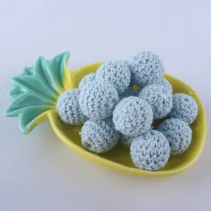 Close-up of 16mm light blue hand-crocheted beads for DIY jewelry on a yellow tray