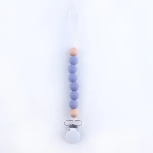 Detail of baby pacifier clip with purple silicone beads and natural wooden accents
