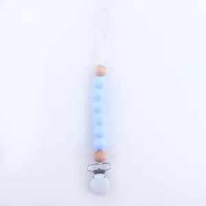 Close-up of light blue silicone beads and natural wooden beads on a baby pacifier clip