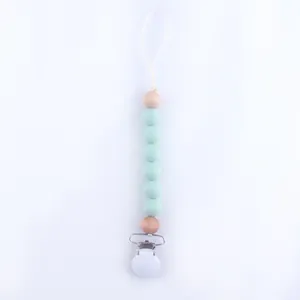 Close-up of mint green silicone beads and natural wood beads on a baby pacifier clip