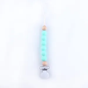 Detail of baby pacifier clip with light blue silicone beads and natural wooden accents