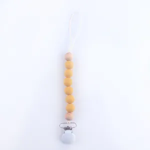 Detail of yellow silicone beads and wooden beads on baby pacifier clip with secure fastener