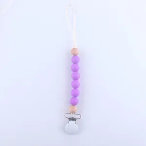 Detail of baby pacifier clip with purple silicone beads and natural wooden accents