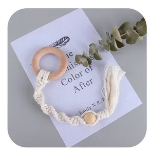 Handmade beech wood baby teether with woven cotton cord and tassel in Nordic boho style