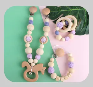 Close-up of silicone and wooden baby pacifier clips and teether set on green background