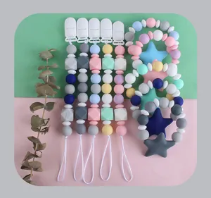 Detailed view of colorful silicone pacifier clips and star teether rings on pastel background