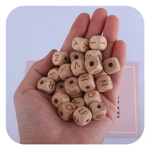 Hand holding natural beech wood alphabet beads for DIY baby pacifier clips and crafts