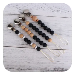 Set of four minimalist pacifier clips with silicone and beech wood beads on wood background