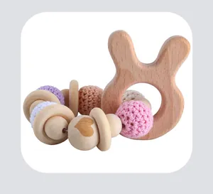Detail of wooden bunny teether and crochet bead rattle in soft pastel pink tones