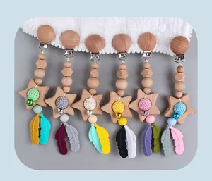 Detail of wooden baby pacifier clips with silicone feathers and crochet star beads