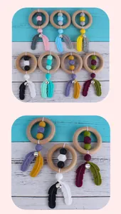 Detail of wooden baby rattle with colorful silicone beads and feather-shaped teether charms