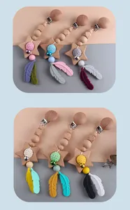 Detail of DIY baby pacifier clips featuring star wood beads and silicone feather charms
