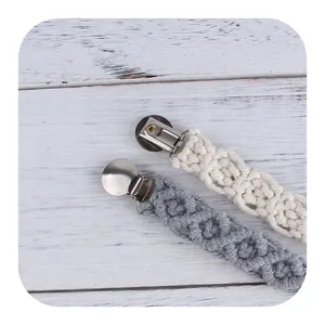 Catenelle per ciuccio in cotone intrecciato beige e grigio su sfondo in legno