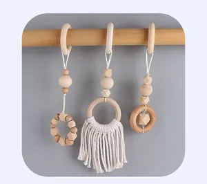 Détail de suspensions pour portique bébé avec anneaux en bois naturel et pompons en coton macramé