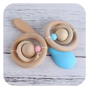 Natural wooden baby rattle and teether set with pink and blue beads on white wood