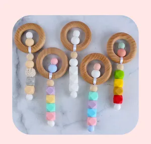 Détail à plat d'un anneau de dentition en hêtre et perles en silicone de couleur macaron