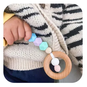 Anneau de dentition pour bébé en bois de hêtre et perles en silicone tenu par enfant
