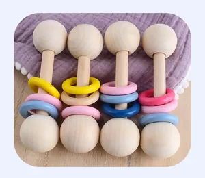 Top view of four natural wood baby rattles with colorful rings on soft purple fabric