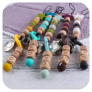 Silicone and beech wood baby pacifier clips with football relief and DAD engraved beads